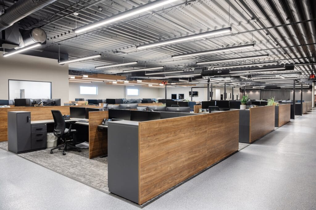 Linear pendant lights line an open floor plan office with rows of workspaces